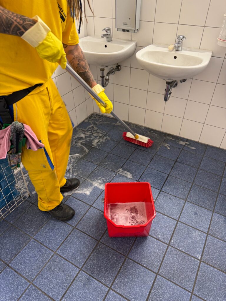Mitarbeiter von Gebäudereinigung Kohl bei der Grundreinigung eines Sanitärbodens