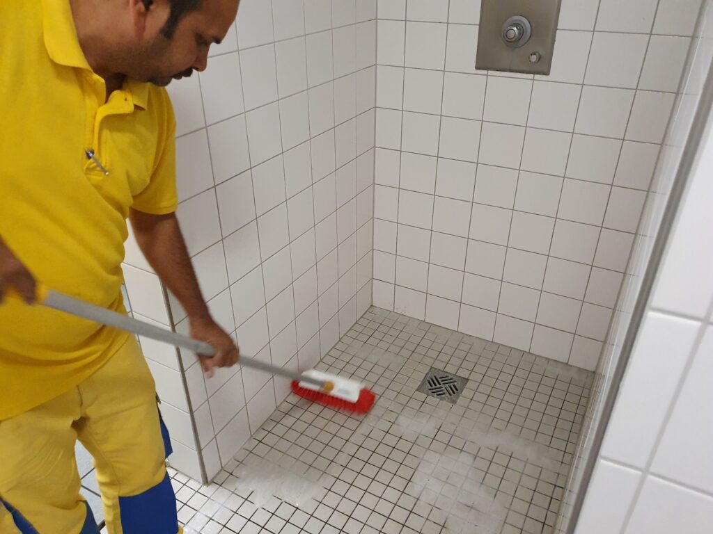 Shaarma von der Thomas Kohl Gruppe bei der sorgfältigen Reinigung eines gefliesten Sanitärbereichs